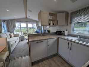 a kitchen with white cabinets and a living room at The Manor in Dunoon