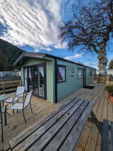 a green tiny house on a deck with a table and chairs at The Manor in Dunoon