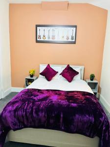 a bedroom with a purple blanket on a bed at Elm Vale Lodge in Liverpool