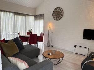 a living room with a couch and a clock on the wall at Groenpark Simpelveld - Castra 33 in Simpelveld