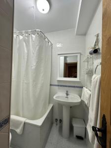 a white bathroom with a sink and a tub and a shower at Casa Rural El Torrejon in Arenas de Cabrales