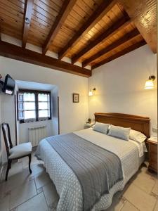 a bedroom with a large bed and a chair at Casa Rural El Torrejon in Arenas de Cabrales