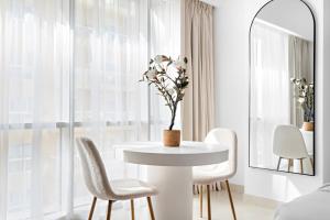 a white dining room with a white table and chairs at Silkhaus Modern Studio Near Silicon Central Mall in Dubai