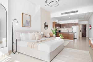 a white bedroom with a large bed and a kitchen at Silkhaus Modern Studio Near Silicon Central Mall in Dubai