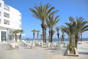 a resort patio with palm trees and chairs and the ocean at Blue Beach Golf and Spa in Monastir