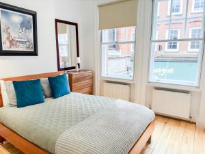 a bedroom with a bed and two windows at Alluring 2-Bed, 2-Bath Flat on High Street Kensington, Near Kensington Palace in London