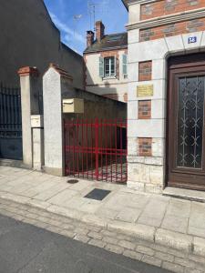 een rode poort aan de zijkant van een gebouw bij Le Nid Arrivé autonome clim wifi linge inclus in Romorantin