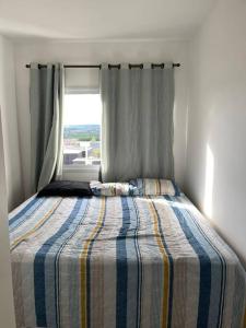 Bett in einem Schlafzimmer mit Fenster in der Unterkunft Apartamento Confortável. Auxílio/dicas na cidade. in Juazeiro do Norte