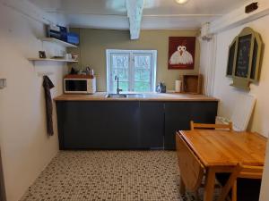 a kitchen with a sink and a microwave and a table at Ringkøbing Fjord B&B in Skjern