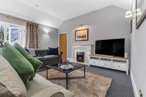 a living room with a couch and a tv and a fireplace at The Old Stables at Port Hill in Medbourne