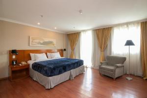 um quarto de hotel com uma cama e uma cadeira em Flat Barra First no Rio de Janeiro
