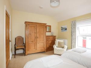 - une chambre avec deux lits, une commode et une chaise dans l'établissement Amelie Cottage, à Beaumaris