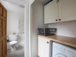 a bathroom with a toilet and a washer and dryer at Amelie Cottage in Beaumaris +27 photos