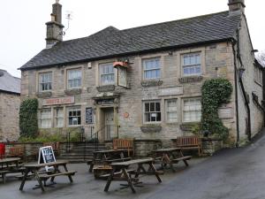 an old stone building with picnic tables in front of it at Harrow Cottage in Bakewell