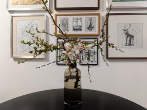un jarrón con flores en una mesa con fotos en Cosy design apartment in the city centre, en Nitra