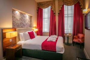 リバプールにあるHeywood House Hotel, BW Signature Collectionのベッドと赤いカーテンが備わるホテルルームです。