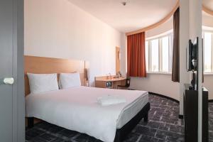 a hotel room with a large bed and a television at Ibis Astana in Astana