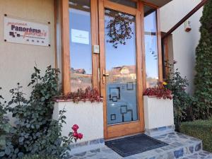 eine Tür zu einem Gebäude mit Blumen davor in der Unterkunft Pension Panorama in Odorheiu Secuiesc