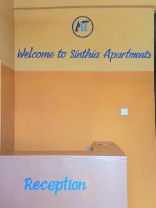 Una señal que dice bienvenido a la recepción de aplicaciones sirminia en Sinthia Hotel Apartments en Chaki Chaki