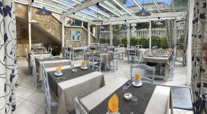 un restaurant avec des tables et des chaises dans un bâtiment dans l'établissement Hôtel Jas Neuf, à Sainte-Maxime