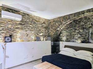 1 dormitorio con cama y pared de piedra en ca' di sotto, en Riomaggiore