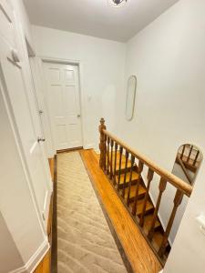 pasillo con escalera de madera y puerta blanca en Stay Rego Park en Rego Park