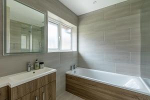 een badkamer met een bad, een wastafel en een spiegel bij Lovely 2BR in peaceful Hampstead, NW London in Londen
