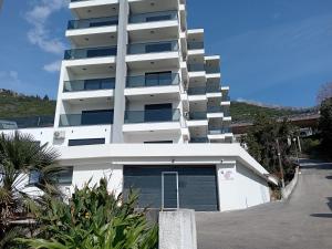 a white apartment building with a garage at Apartmani Seaside in Dobra Voda
