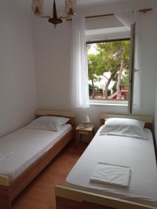 twee bedden in een kamer met een raam bij Guesthouse Dante in Tisno