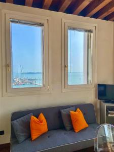 a blue couch with orange pillows in a room with two windows at Miami in Venice in Venice