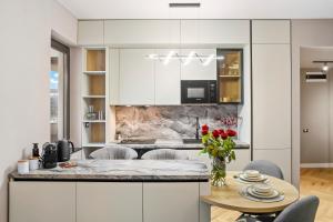 una cucina con armadi bianchi e un tavolo con rose di My Place Residence a Voluntari