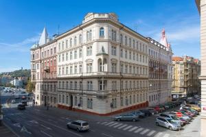 un gran edificio blanco con coches aparcados en un aparcamiento en Place of Grace - 50 Meters from Dancing House en Praga