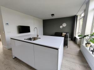 uma cozinha branca com um lavatório e uma sala de estar em K50173 Modern apartment near the center em Eindhoven