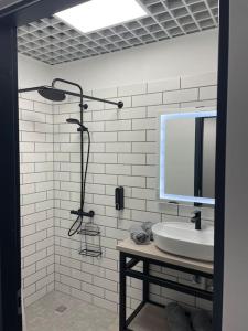 a bathroom with a shower with a sink and a mirror at Apartment Loftas13-6 in Kretinga
