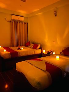 a room with three beds with candles and lights at Eco Adventure Resort in Sauraha