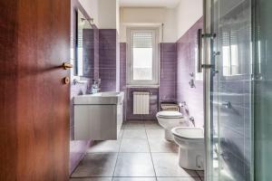 une salle de bains pourpre avec toilettes et lavabo. dans l'établissement green oasis in milan - luxury appartment free wifi - Policlinico San Donato, à San Donato Milanese