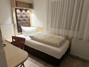 a small bedroom with a bed and a table at Hotel Haase in Hannover