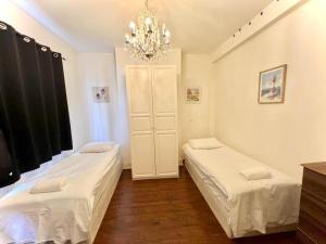a bedroom with two beds and a chandelier at Canary Wharf Home stay in London