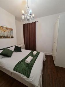 a bedroom with a large bed with green sheets and a chandelier at Canary Wharf Home stay in London