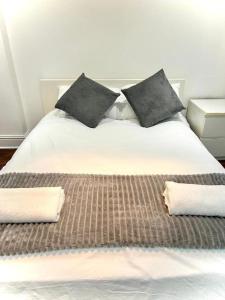 a large white bed with two pillows on it at Canary Wharf Home stay in London