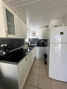 een keuken met witte kasten en een witte koelkast bij La Discrète toute équipée avec piscine in Gruissan +1 foto