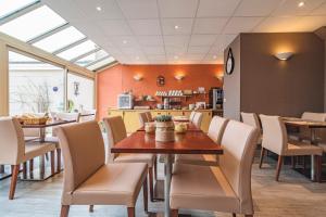 uma sala de jantar com mesa e cadeiras em Logis Hotel au tambour em Reims