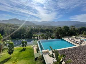 Blick auf einen Pool mit Bergen im Hintergrund in der Unterkunft Camburizinho 3 suítes Beach Tenis in São Sebastião
