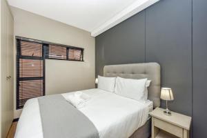 1 dormitorio con cama blanca y ventana en Easy Stay - The Vantage Rosebank, en Johannesburgo