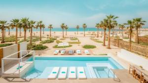 una piscina con palmeras y una playa en Nikki Beach Resort & Spa Dubai en Dubái