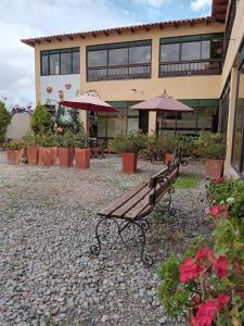 a park bench in front of a building with umbrellas at Hotel Villa Sofia in Nobsa