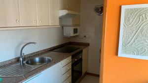 a small kitchen with a sink and a microwave at Precioso ático en Playa América a 200 metros de la playa in Nigrán