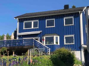 a blue house with a blue deck in front of it at Mountain view Apartment near Oslo: bedroom, lounge, kitchen and bathroom. Flat in Rykkinn in Kolsås
