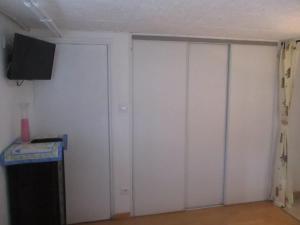 een kamer met witte muren en een deur met een televisie bij le gite fleuri in Abbeville