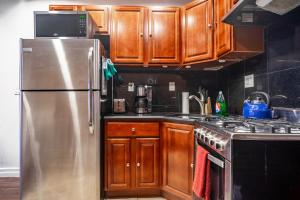 a kitchen with wooden cabinets and a stainless steel refrigerator at The Nest- 1 bedroom 1 bath convenient and cozy apartment in Brooklyn